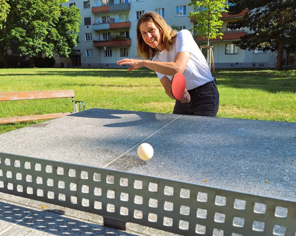Eine Frau spielt an einem grauen Tisch Tischtennis.